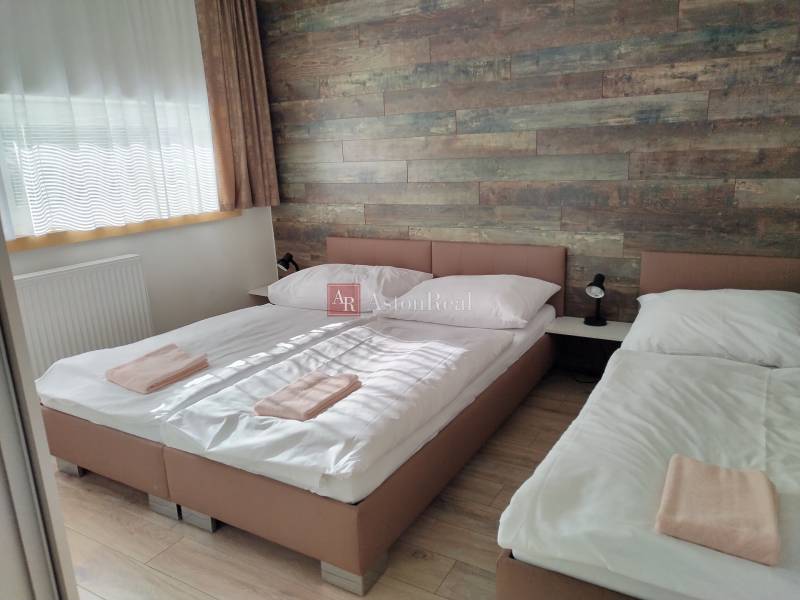 NOVOSTAVBA: 6-izbová CHATA, VL pozemok 484 m2 v Martine  - Izba v chate s dvoma posteľami, drevenou stenou a podlahou s dreveným dekorom.