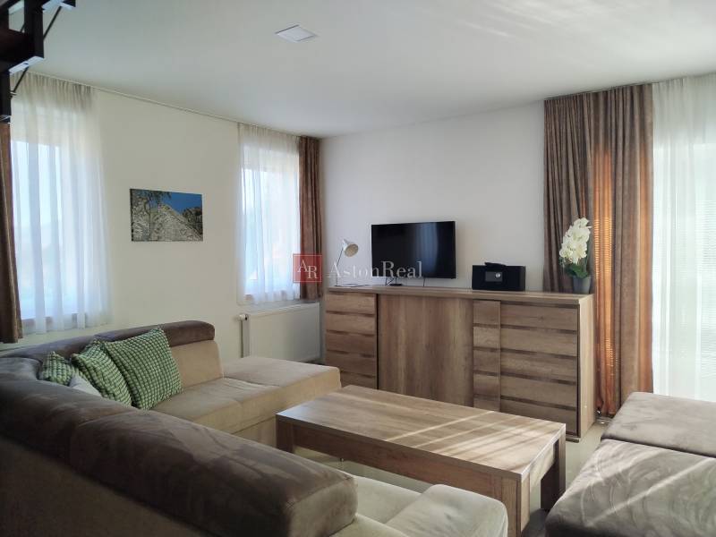 NOVOSTAVBA: 6-izbová CHATA, VL pozemok 484 m2 v Martine  - Svetlá izba v chate s pohodlnou sedačkou a podlahou s dreveným dekorom.