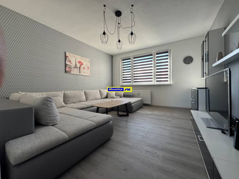 3 izbový zrekonštruovaný byt na prenájom - Martin - Obývacia izba v 3-izbovom byte s pohovkou a podlahou s dreveným dekorom.