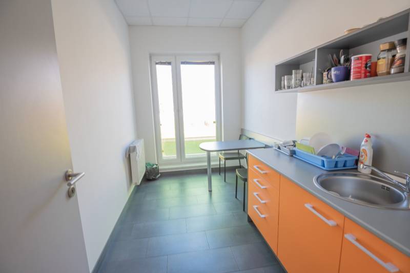Na prenájom kancelária  15 m²,  v novostavbe, Odborárska ulica, voľná - Kuchynka v kancelárii s oranžovými skrinkami, drezom a stolíkom na sedenie.