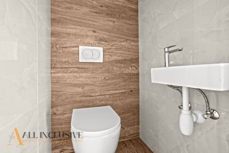 ALL INCLUSIVE I 3 IZBOVÉ BYTY S TERASOU, SO ZÁHRADOU + 2 PARK. MIESTA - Toaleta s podlahou s dreveným dekorom a bielym umývadlom v 3-izbovom byte.