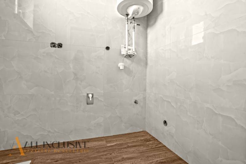 ALL INCLUSIVE I 3 IZBOVÉ BYTY S TERASOU, SO ZÁHRADOU + 2 PARK. MIESTA - Kúpeľňa s vodným ohrievačom a podlahou s dreveným dekorom v 3-izbovom byte.