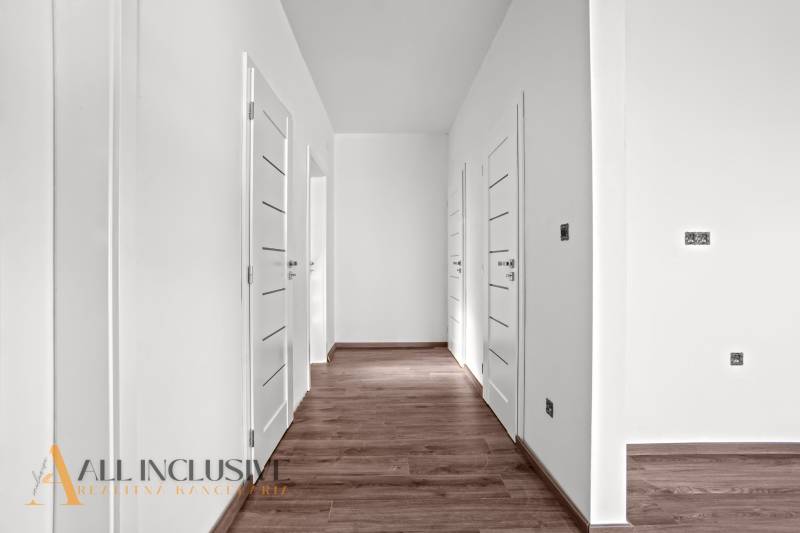 ALL INCLUSIVE I 3 IZBOVÉ BYTY S TERASOU, SO ZÁHRADOU + 2 PARK. MIESTA - Chodba v 3-izbovom byte s bielymi dverami a podlahou s dreveným dekorom.
