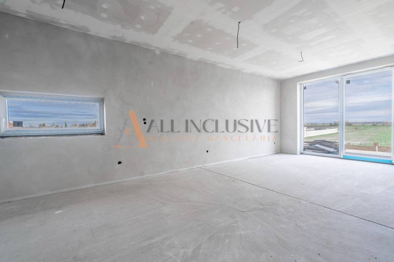 ALL INCLUSIVE I 3 IZBOVÉ BYTY S TERASOU, SO ZÁHRADOU + 2 PARK. MIESTA - Priestranná miestnosť v 3-izbovom byte, s veľkým oknom a bielymi stenami.