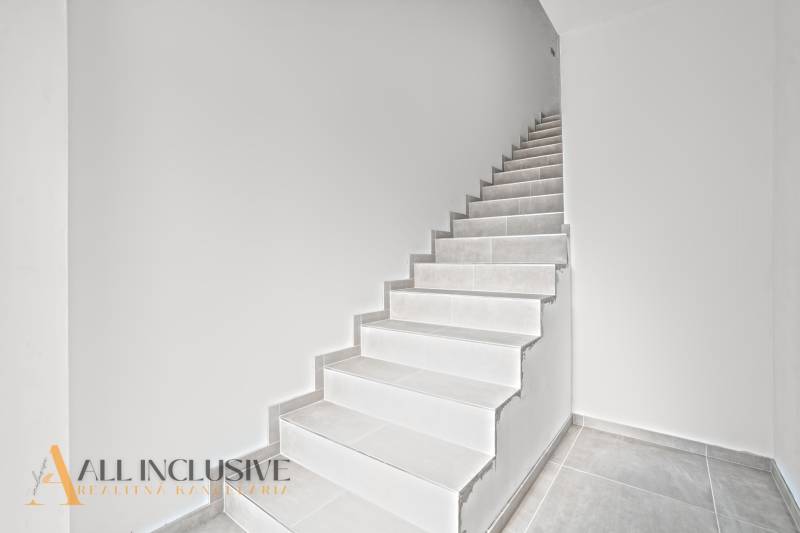 ALL INCLUSIVE I 3 IZBOVÉ BYTY S TERASOU, SO ZÁHRADOU + 2 PARK. MIESTA - Schodisko s bielymi stenami a dlažbou v 3-izbovom byte.