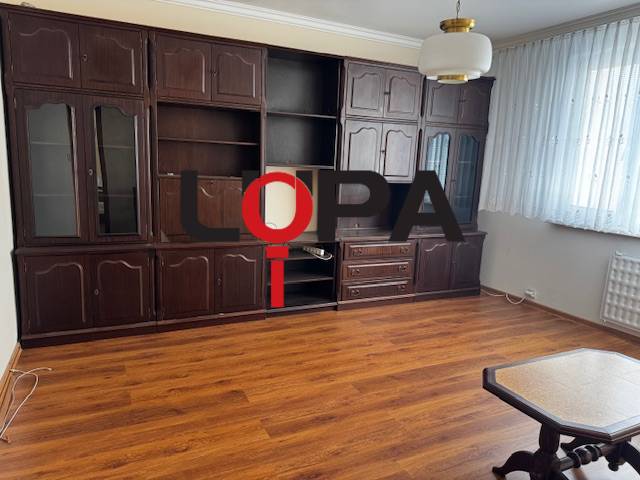 Prenájom 3izb. zariadeného bytu na Jazdeckej ul., Nové Zámky - Obývacia izba v 3-izbovom byte s podlahou s dreveným dekorom, tmavý nábytok.