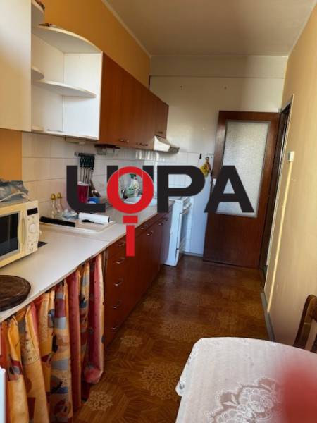 Prenájom 3izb. zariadeného bytu na Jazdeckej ul., Nové Zámky - Kuchyňa v 3-izbovom byte s podlahou s dreveným dekorom, biele skrinky, jedálenský stôl.