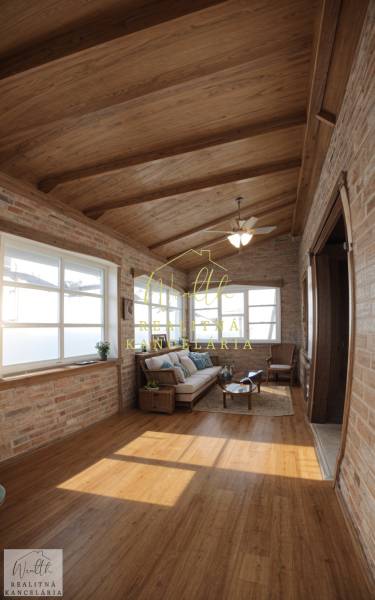 Vidiecky dom v Zemplínskej Teplici - Interiér rodinného domu s tehlovými stenami, podlahou s dreveným dekorom a pohodlným sedením.