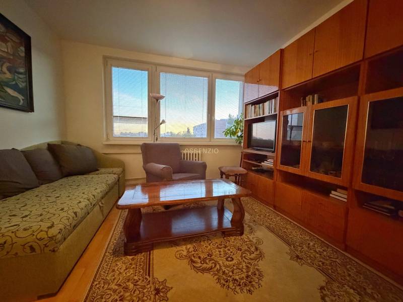 - PREDAJ - 3 izbový byt - Estónska ul. - Vrakuňa  - Obývacia izba s pohovkou, kreslom, dreveným nábytkom a podlahou s dreveným dekorom v 3-izbovom byte.