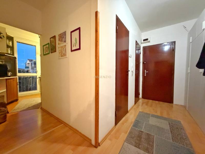 - PREDAJ - 3 izbový byt - Estónska ul. - Vrakuňa  - Chodba 3-izbového bytu s podlahou s dreveným dekorom, obrazy na stenách.