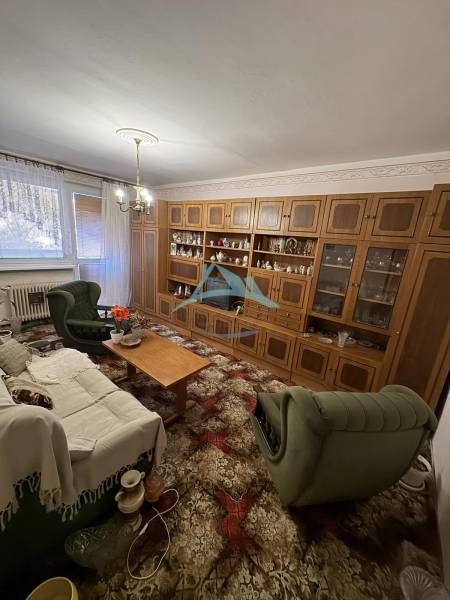 Šahy – 3i Byt v Centre Mesta s Balkónom  - Obývačka v 3-izbovom byte s drevenou obývacou stenou a zeleným nábytkom.