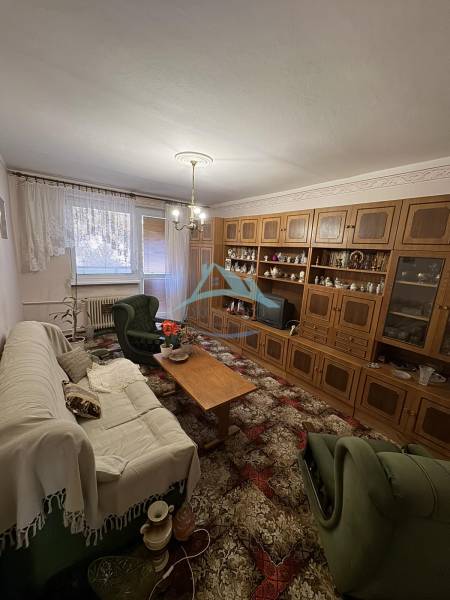 Šahy – 3i Byt v Centre Mesta s Balkónom  - Obývačka v 3-izbovom byte s drevenou obývacou stenou a pohodlným sedením.