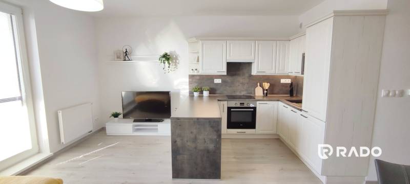 | 2-izbový byt, ul. Predmerského VINOHRADY | Trenčín  - Obývacia izba s kuchynským kútom, svetlá podlaha s dreveným dekorom v 2-izbovom byte.