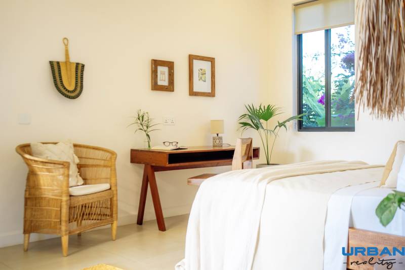 LUXURY 2-BEDROOM VILLA IN PAJE - Svetlá spálňa v rodinnom dome s ratanovým kreslom a dreveným stolom.