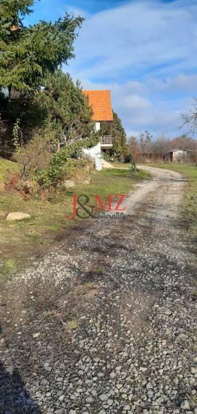 Pozemok 5.200 m2 , šírka 35 m, Horné Jabloňovce (SM - 849)   - Rekreačné pozemky Horné Jabloňovce v Jabloňovciach s chodníkom vedľa malého domu a stromami.