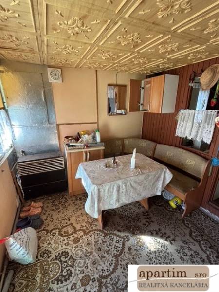 Apartim predá záhradu s možnosťou výstavby na Strednej ul v Ružinove - Interiér chaty so starožitným vzorovaným stolom a drevenými detailami v Záhradách.