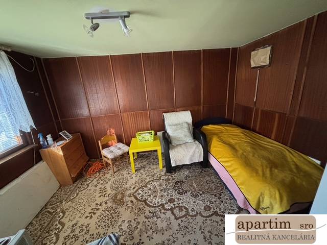 Apartim predá záhradu s možnosťou výstavby na Strednej ul v Ružinove - Izba so stoličkami, lôžkom, skrinkou a dekoratívnym kobercom v Záhradách.