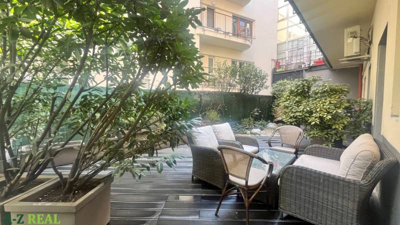 Prenájom nadštandardne zariadených kancelárií  v centre, 151 m2 - Na ulici Radlinského terasa s ratanovým nábytkom, rastliny, okná kancelárie v pozadí.