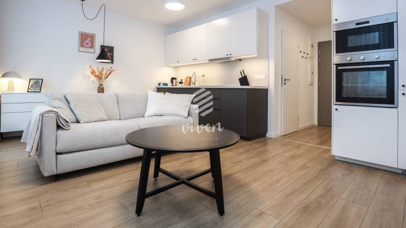 PRENÁJOM - 1 izbový byt v projekte Ovocné sady - Obývacia izba s kuchynským kútom v 1-izbovom byte, podlaha s dreveným dekorom.