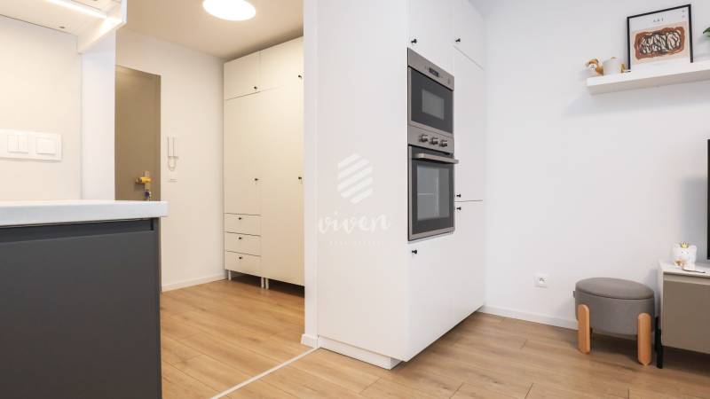 PRENÁJOM - 1 izbový byt v projekte Ovocné sady - Kuchyňa v 1-izbovom byte s bielymi skrinkami a podlahou s dreveným dekorom.