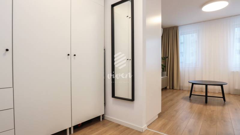 PRENÁJOM - 1 izbový byt v projekte Ovocné sady - Nábytok v 1-izbovom byte s podlahou s dreveným dekorom a čiernym stolíkom.