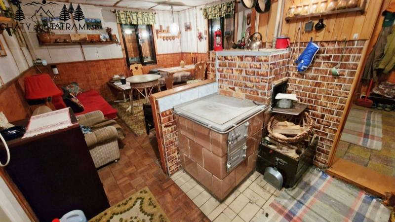 Útulná chata polosamota Tále Nízke Tatry - Interiér chaty s tradičným tehlovým sporákom, podlahou s dreveným dekorom a pohodlným posezením.