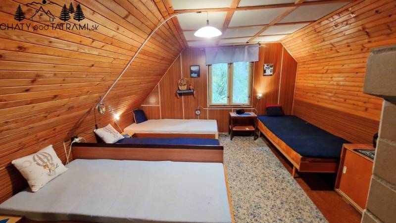 Útulná chata polosamota Tále Nízke Tatry - Drevený interiér chaty s tromi jednolôžkovými posteľami a krajinným obrazom.
