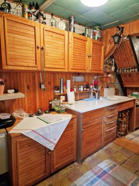 Útulná chata polosamota Tále Nízke Tatry - Kuchyňa v chate s drevenými skrinkami a bielym pracovným pultom, útulná atmosféra.