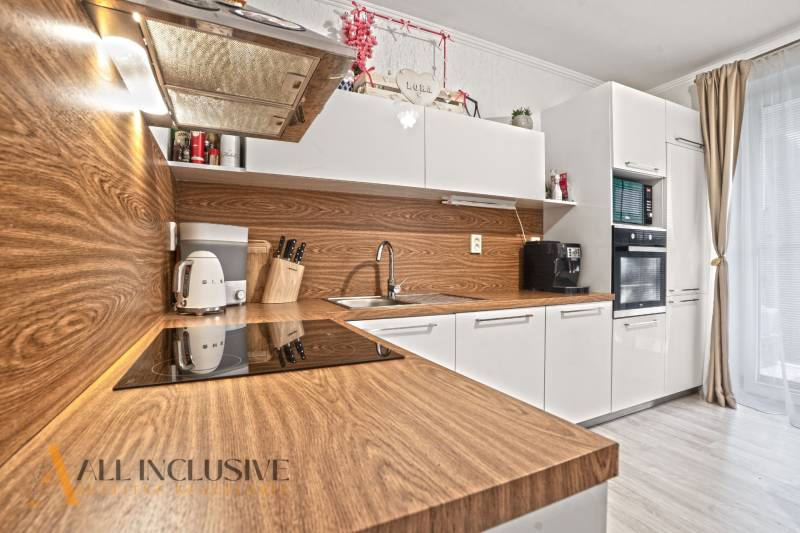 NA PREDAJ 3-IZB. BYT S TERASOU A ZÁHRADKOU, DUN.STREDA - Kuchyňa v 3-izbovom byte s bielymi skrinkami a podlahou s dreveným dekorom.