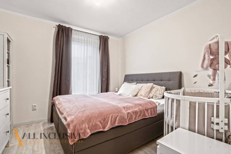 NA PREDAJ 3-IZB. BYT S TERASOU A ZÁHRADKOU, DUN.STREDA - Spálňa v 3-izbovom byte s posteľou a detskou postieľkou, podlaha s dreveným dekorom.