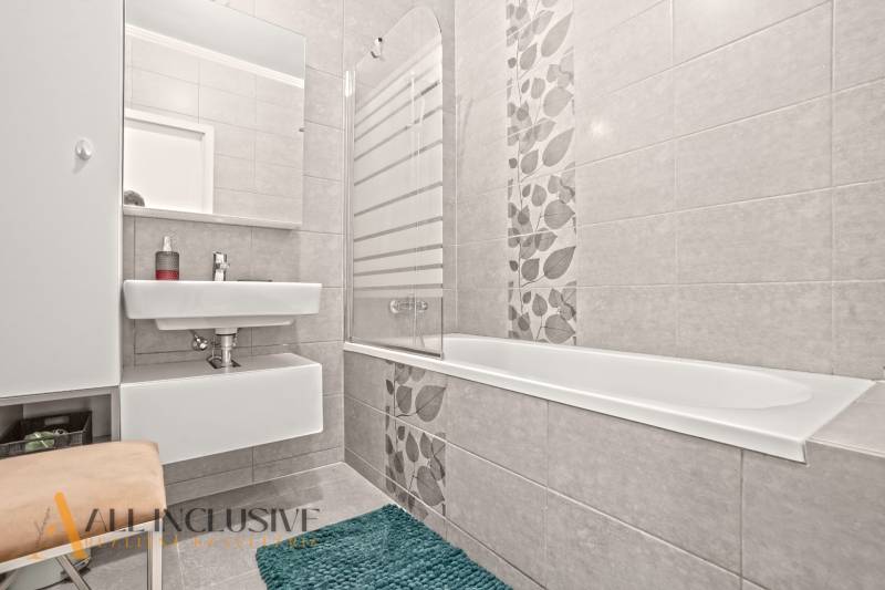 NA PREDAJ 3-IZB. BYT S TERASOU A ZÁHRADKOU, DUN.STREDA - Kúpeľňa v 3-izbovom byte so sprchovou vaňou, umývadlom a dekoratívnymi dlaždicami na stenách.