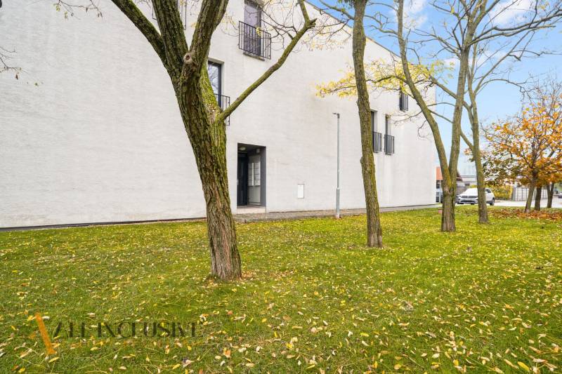 NA PREDAJ 3-IZB. BYT S TERASOU A ZÁHRADKOU, DUN.STREDA - Exteriér 3-izbového bytu v Dunajskej Strede s trávnikom a stromami počas jesene.