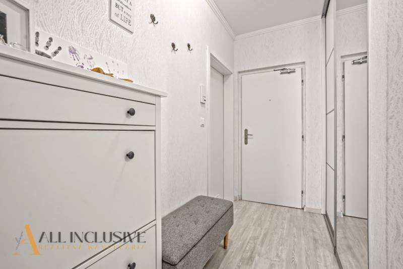 NA PREDAJ 3-IZB. BYT S TERASOU A ZÁHRADKOU, DUN.STREDA - Chodba v 3-izbovom byte s bielym nábytkom a podlahou s dreveným dekorom.