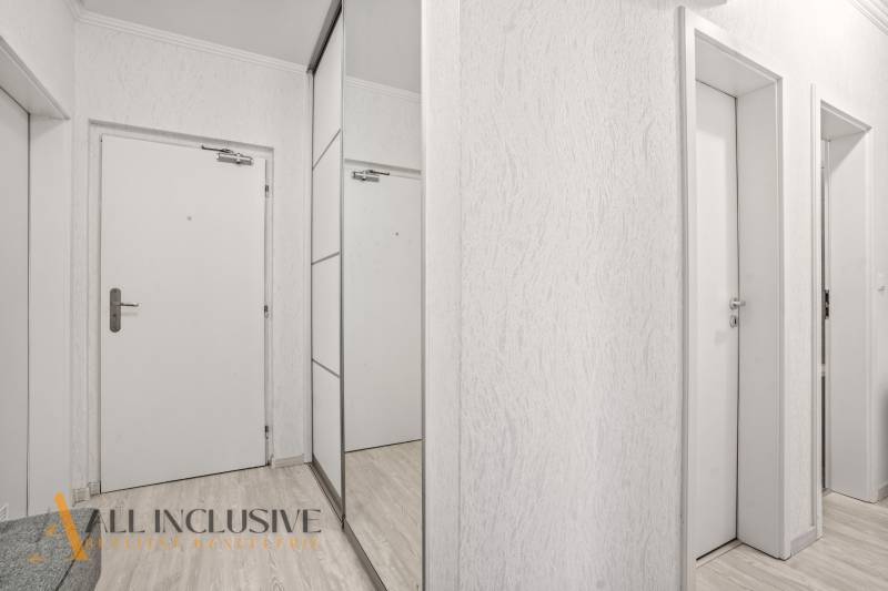 NA PREDAJ 3-IZB. BYT S TERASOU A ZÁHRADKOU, DUN.STREDA - Biele interiérové dvere a zrkadlová skriňa v 3-izbovom byte s podlahou s dreveným dekorom.