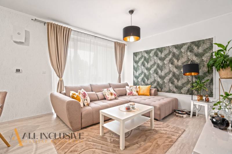 NA PREDAJ 3-IZB. BYT S TERASOU A ZÁHRADKOU, DUN.STREDA - Obývačka s béžovou sedacou súpravou, bielym stolíkom a tapetou s prírodným motívom.