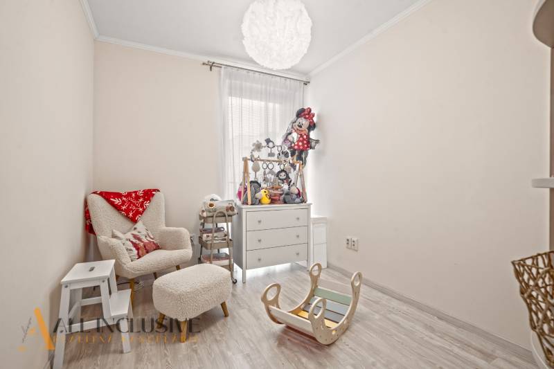 NA PREDAJ 3-IZB. BYT S TERASOU A ZÁHRADKOU, DUN.STREDA - Detská izba v 3-izbovom byte s pohodlným kreslom a hračkami, podlaha s dreveným dekorom.