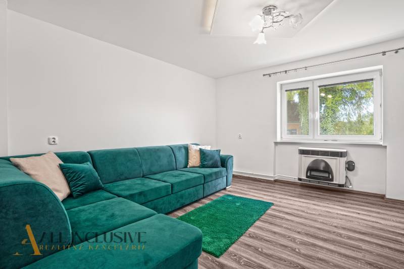 NA PREDAJ 4+1-IZBOVÝ ROD. DOM, VEĽKÉ KOSIHY - Obývacia izba v rodinnom dome s tyrkysovou sedačkou a podlahou s dreveným dekorom.