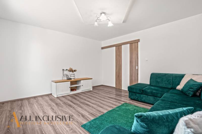 NA PREDAJ 4+1-IZBOVÝ ROD. DOM, VEĽKÉ KOSIHY - Interiér rodinného domu s podlahou s dreveným dekorom, zelenou sedačkou a stolíkom.