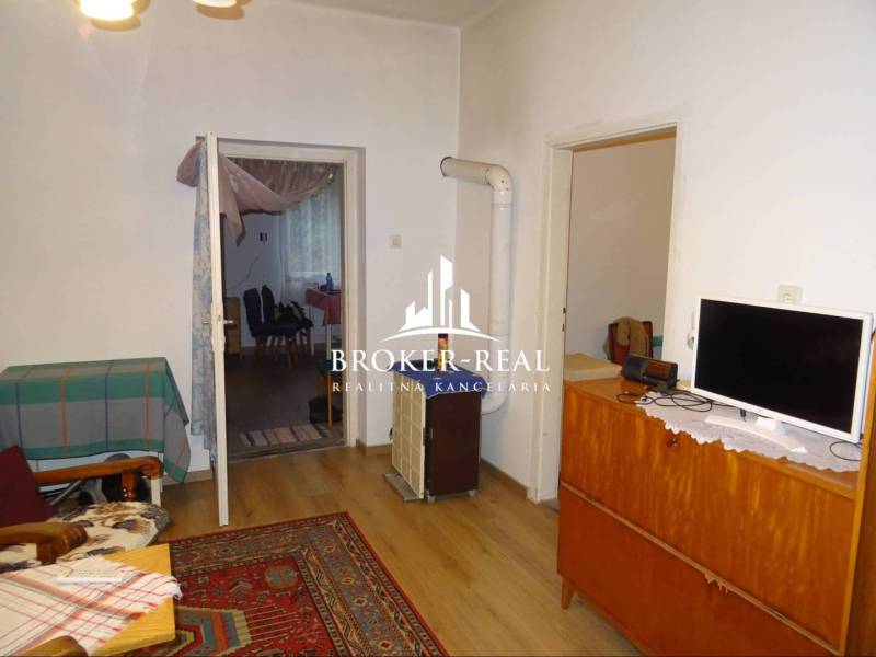 Rodinný dom, chalupa 2 Izbový - Fony - Obývacia izba v rodinnom dome s kobercom a podlahou s dreveným dekorom.