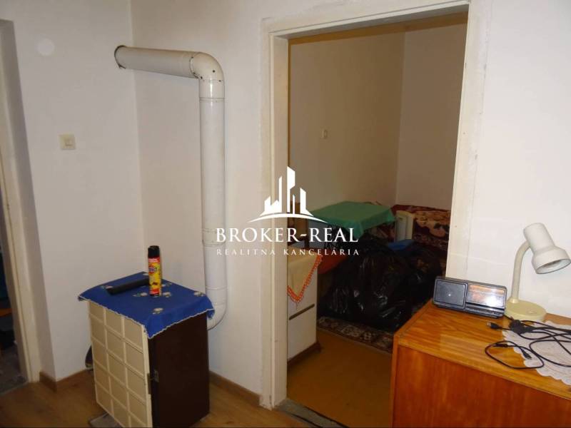 Rodinný dom, chalupa 2 Izbový - Fony - Interiér rodinného domu s vykurovacím telesom, nábytkom a podlahou s dreveným dekorom.