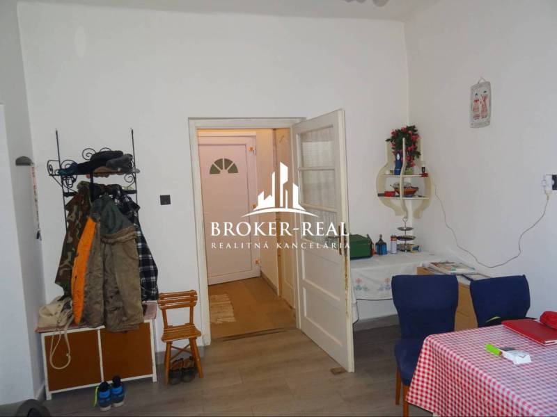 Rodinný dom, chalupa 2 Izbový - Fony - Interiér rodinného domu s podlahou s dreveným dekorom, jedálenským stolom a vešiakom na oblečenie.