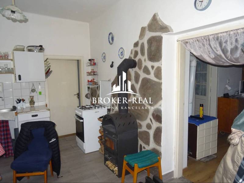 Rodinný dom, chalupa 2 Izbový - Fony - Kuchyňa v rodinnom dome so sporákom, pecou a kamenným obkladom pri stene.