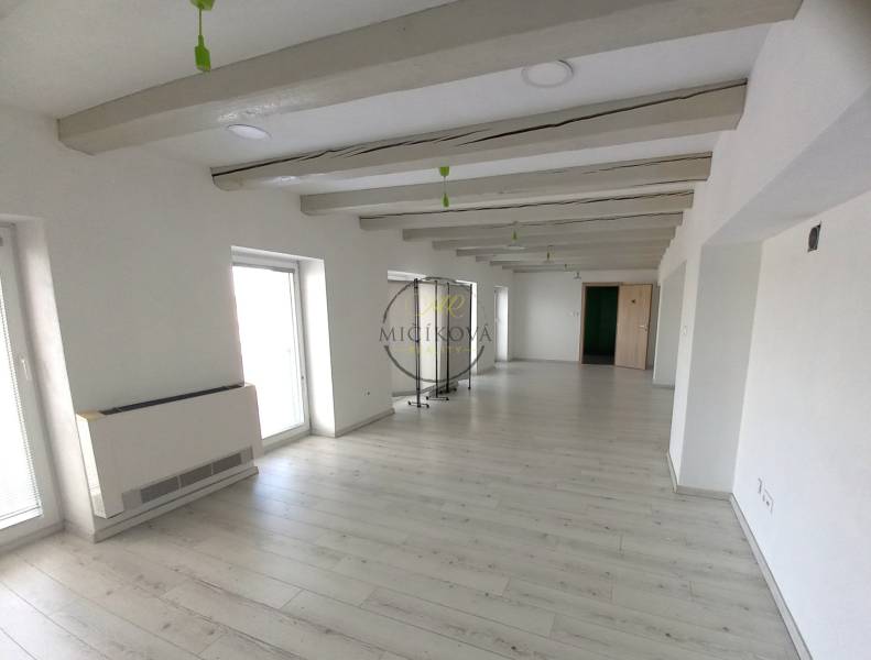 Prenajmeme kancelársky priestor, 40 m2, Levická ul., Vráble - Biela kancelária s podlahou s dreveným dekorom, dekoratívnymi trámami a svetlými stenami.