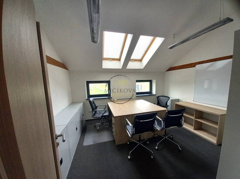Ponúkame na prenájom kanceláriu, 15,54 m2, Levická ul., Vráble - Kancelária s podlahou s dreveným dekorom, strešnými oknami a stolmi so stoličkami.