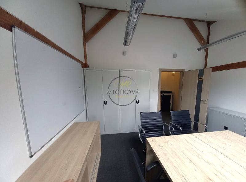 Ponúkame na prenájom kanceláriu, 15,54 m2, Levická ul., Vráble - Kancelárie so stolom, čiernymi stoličkami, skrinkami a bielou tabuľou.