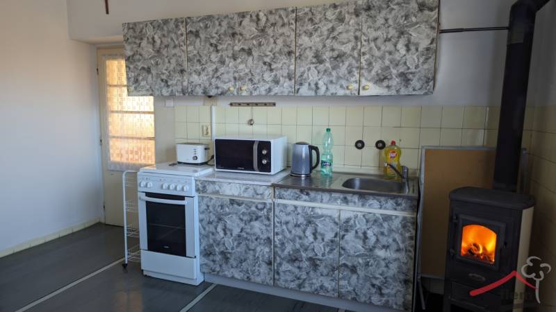 5-izbový rodinný dom na predaj v Hornom Ohaji, okr. NR, pozemok 1251m2 - Kuchyňa s obkladom, sporákom a krbom v rodinnom dome, podlaha s dreveným dekorom.