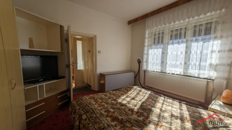 5-izbový rodinný dom na predaj v Hornom Ohaji, okr. NR, pozemok 1251m2 - Spálňa v rodinnom dome s televízorom a kvetinovým vzorom posteľnej bielizne.