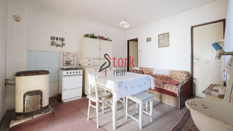 Menší rodinný dom len pár metrov od centra mesta Rajec - Jedáleň s plynovým sporákom, stolom a pohovkou v rodinnom dome, podlaha s dreveným dekorom.