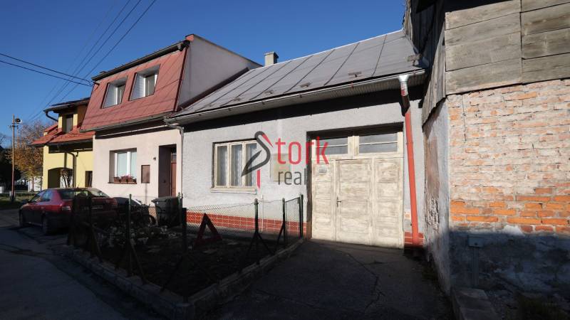 Menší rodinný dom len pár metrov od centra mesta Rajec - Rodinný dom na Kostolnej ulici v Rajci s autom vpredu a dreveným plotom.