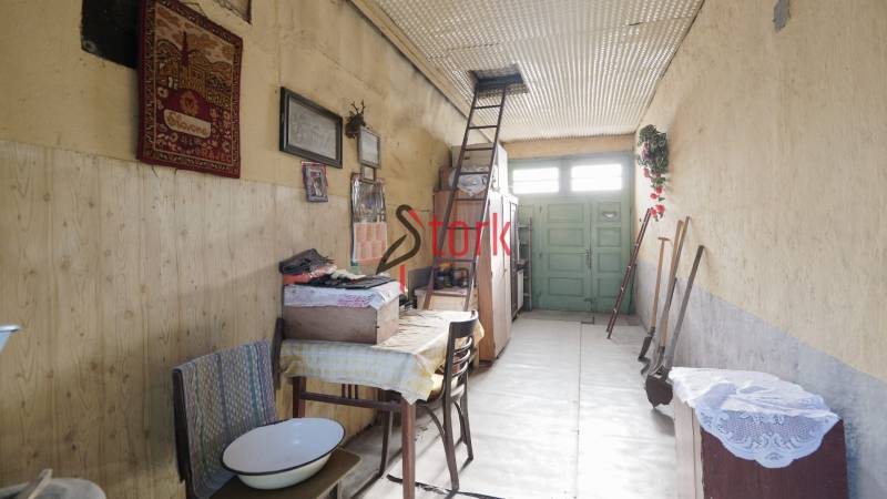 Menší rodinný dom len pár metrov od centra mesta Rajec - Interiér rodinného domu s rebríkom vedľa vyšívanej tapiserie. Podlaha s dreveným dekorom.